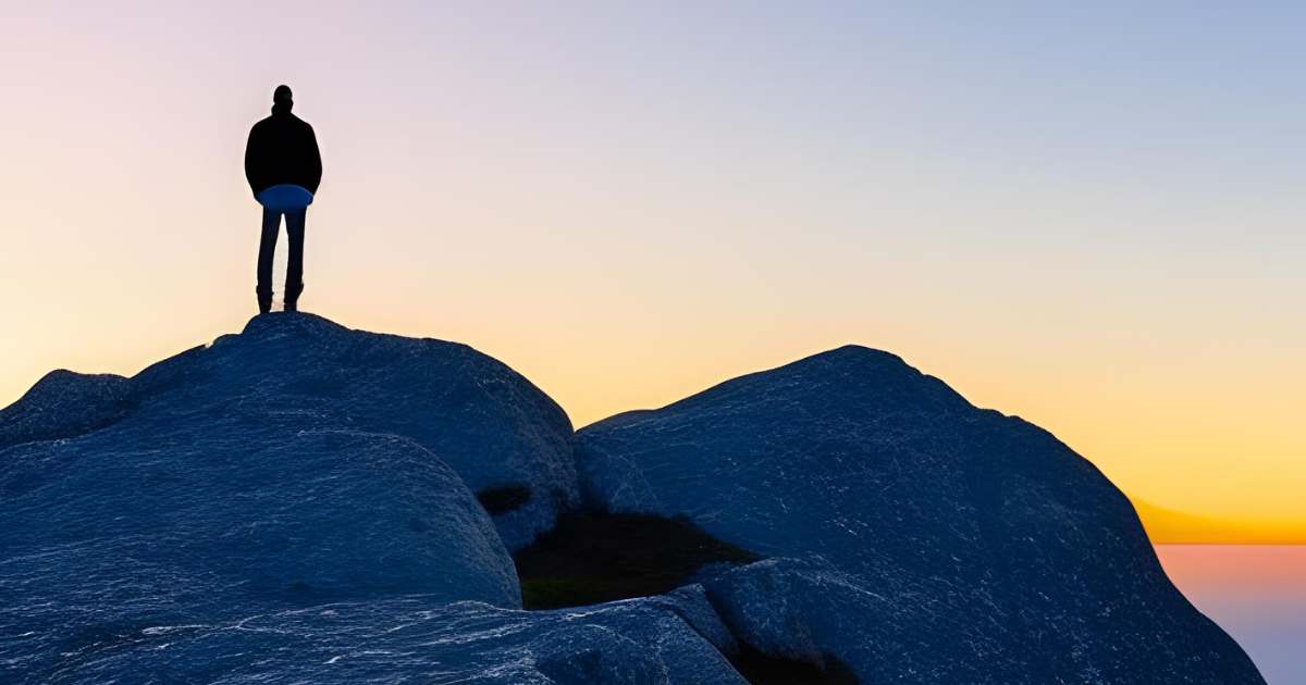 Person on mountain peak with optimistic outlook, symbolizing the power of a positive mindset to achieve dreams